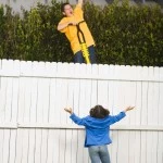 Kid Scaling Fence With Pogo Stick - Credit- Blend Images - 77136517